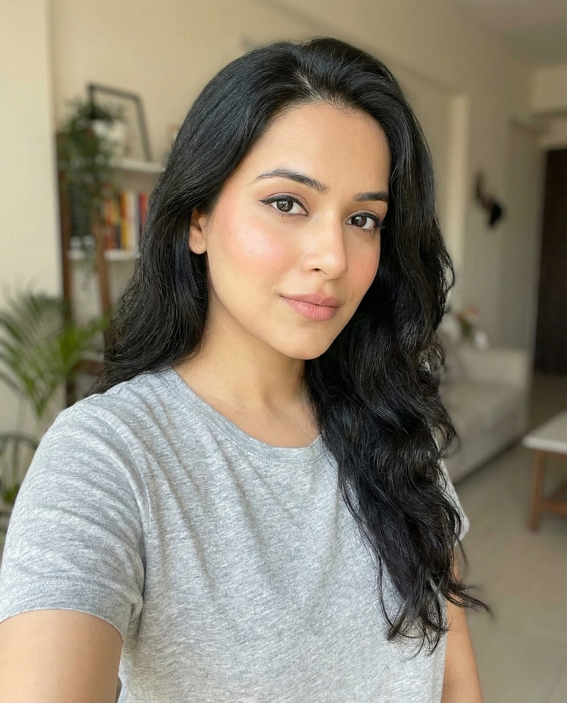 CozyVora customer review profile picture featuring a woman with long dark wavy hair wearing comfortable grey loungewear and minimal makeup in a modern home setting.